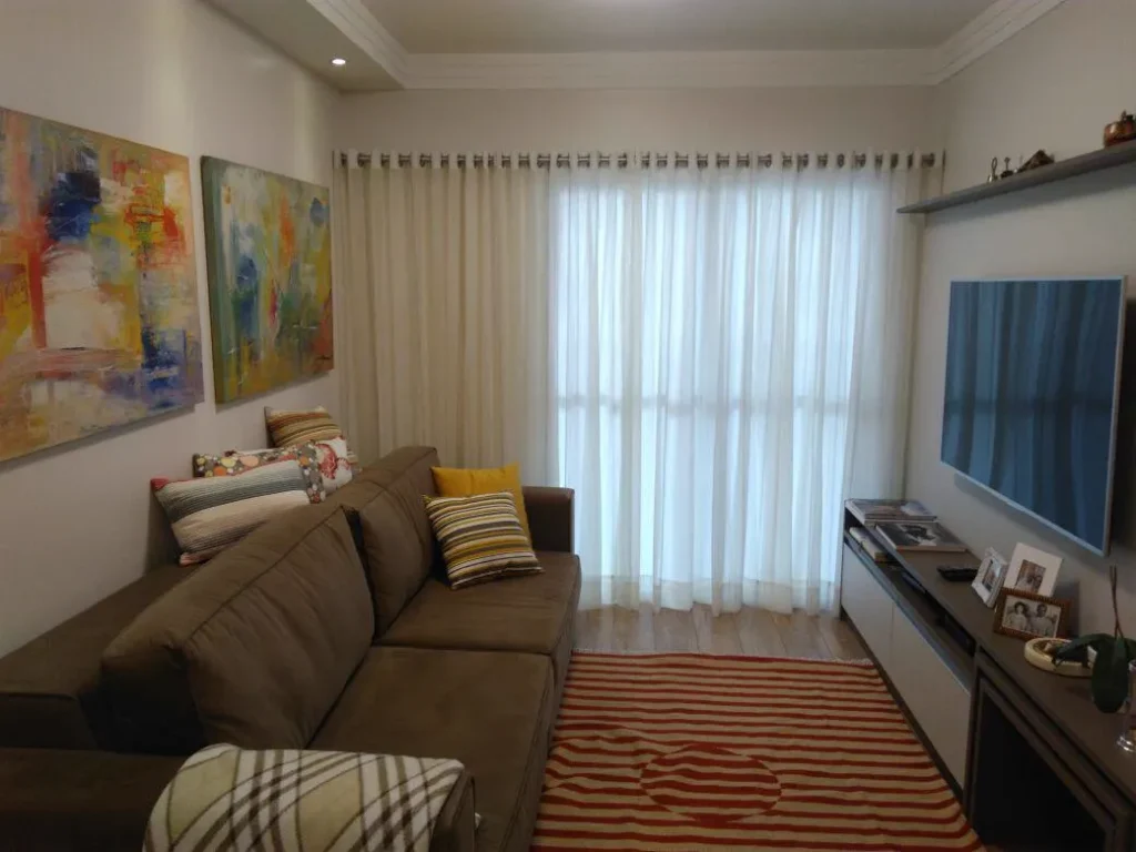 Cortina de voil branca em sala de TV com sofá marrom